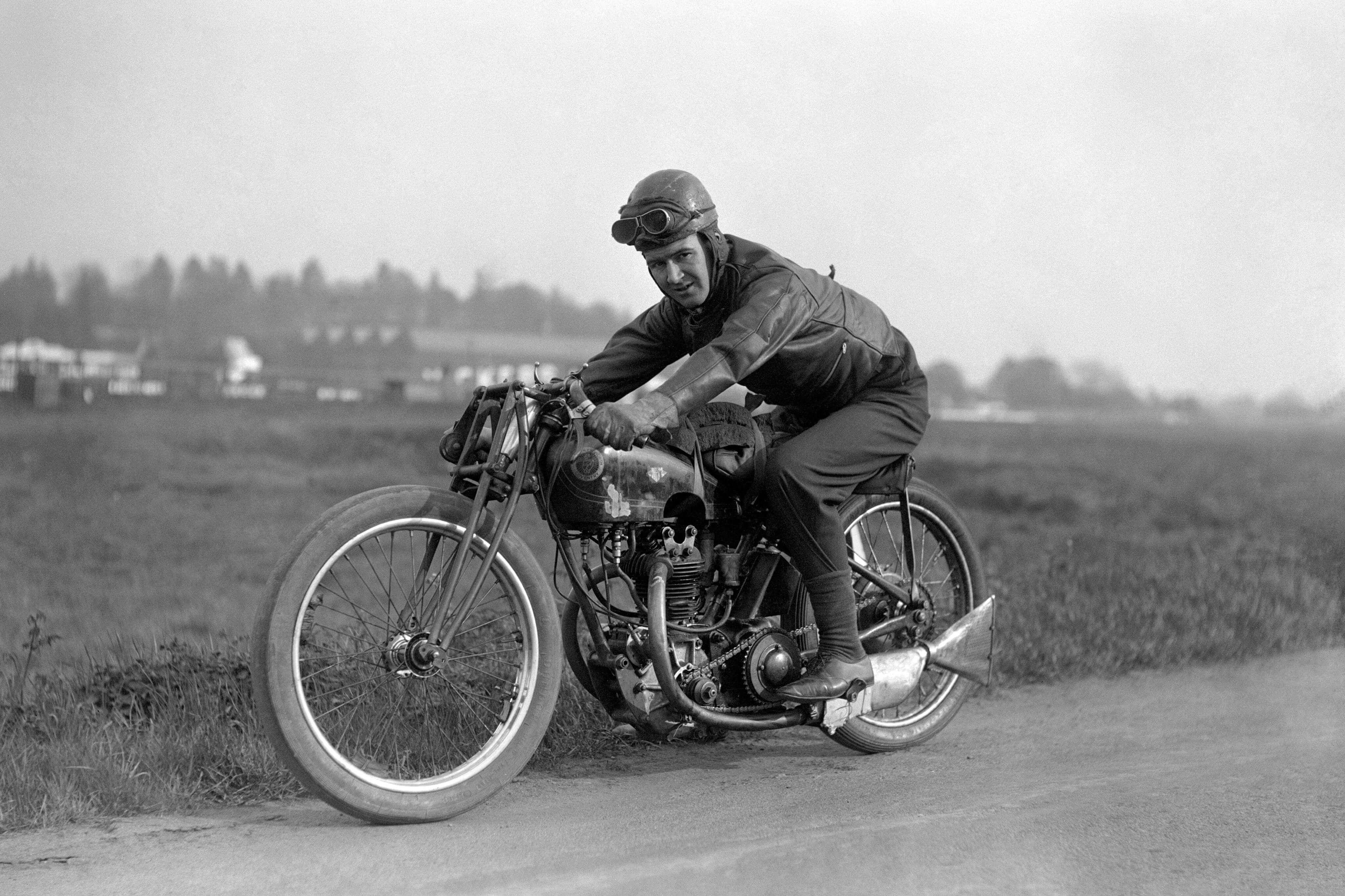 Vintage black and white photo of a person riding a motorcycle on a road.